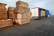 成堆的木材和满载的卡车