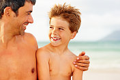 快乐的男人和他的儿子在海滩上