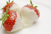 白色盘子上放着裹着巧克力的草莓