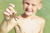 小男孩在萨尼贝尔岛附近的水中发现海星