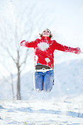 女人在冬天被雪包围着跳跃。