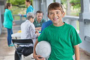 小男孩拿着足球在公园的体育注册