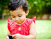 一个刚学走路的印度小女孩用手机在户外拍照