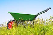 轻型塑料花园手推车在草地上对抗蓝天