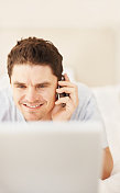 微笑的男人用手机和笔记本电脑