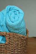 蓝色毛巾卷在棕色编织柳条篮子