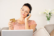 成熟的女士用信用卡和手机在网上购物