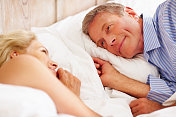 面带微笑的老人躺在床上的一个女人旁边