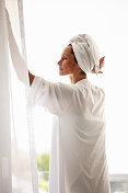 穿着浴袍的成熟女性在窗边放松