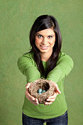 一个年轻女子拿着一个有蛋的知更鸟窝。