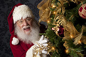 真正的圣诞老人在圣诞树周围偷偷摸摸的照片