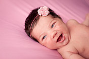 微笑着的新生女婴，粉红色的背景