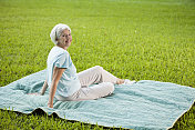 坐在野餐毯子上的老妇人
