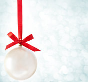 白色的圣诞球挂在红色的丝带上