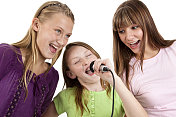 三个十几岁的女孩喜欢用麦克风唱歌。