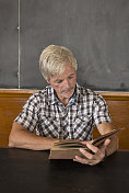 老师在黑板前学习旧书。
