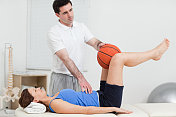 理疗医师把一个球放在女人的膝盖之间