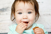 穿着蓝色裙子的小女孩正在吃饼干