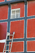 油漆工的梯子倚在旧的半木房子上
