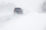 暴风雪在冬季森林的道路上