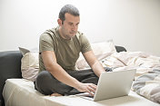 一个男人在床上用笔记本电脑