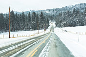 双车道高速公路，冰雪覆盖的蒙大拿山脉森林