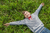 小男孩躺在草地上笑着