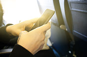 一名女性在飞机上使用智能手机