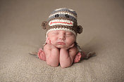 新生儿睡在编织猴帽