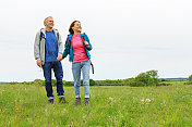 积极成熟的情侣带着背包在绿色的大自然中徒步旅行
