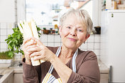 厨房里的年长妇女用欧芹香草和芦笋