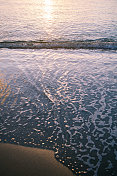 岸边的海水，里面倒映着夕阳