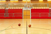 红色体育馆拼花地板上的两个篮球
