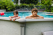 两个孩子在后院的游泳池里玩