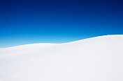 晴朗的天空下，白雪覆盖着小山