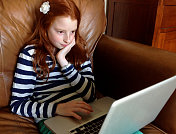 一个女孩在轻松的家庭环境中使用笔记本电脑