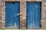 两扇蓝色木质风化门，砖墙