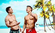 两个兴高采烈的男人站在海滩前
