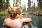 在温泉中享受天然沐浴的年轻女子。