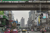 曼谷街道上有汽车、摩托车、商店和摩天大楼。