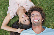 一对年轻夫妇躺在草地上大笑