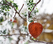 心形的圣诞装饰品挂在白雪覆盖的圣诞树上