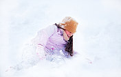 小女孩高兴地在雪地里打滚