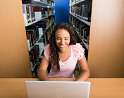 拿着笔记本电脑在图书馆微笑的大学生