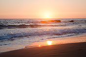 日落时金色海岸上的波浪