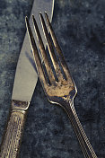 生锈表面上的老旧的叉子和刀