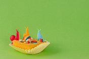 扁平纸杯蛋糕在绿色背景与彩色蜗牛和糖果