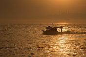 船的剪影在日落与雾在土耳其伊斯坦布尔