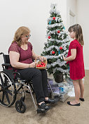 坐在轮椅上的妇女和她的女儿一起装饰圣诞树