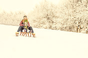 小男孩和他的妈妈在雪地上拉雪橇